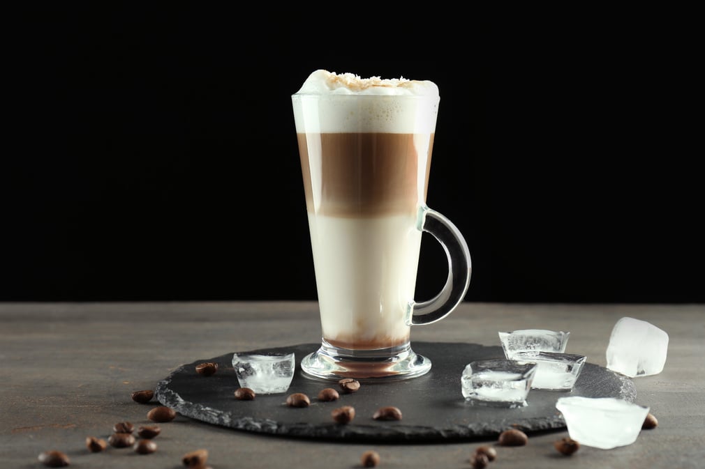 Glass with Caramel Macchiato and Ice Cubes on Slate Plate